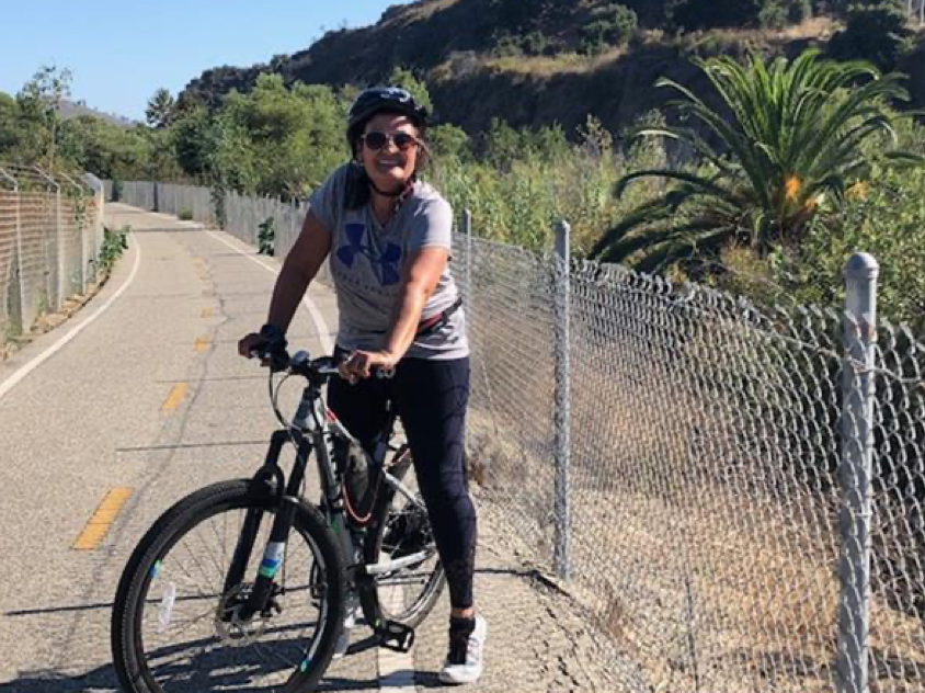 Woman wearing a helmet standing and holding a bike with her two hands